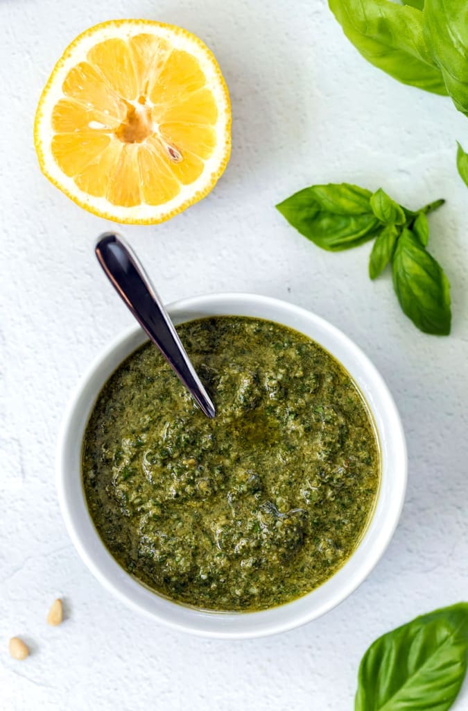 Bowl of Pesto di Basilico in a white bowl with a spoon.