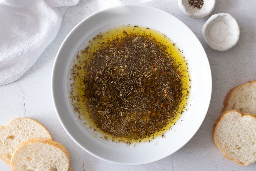 Olive oil bread dip next to slices of bread.