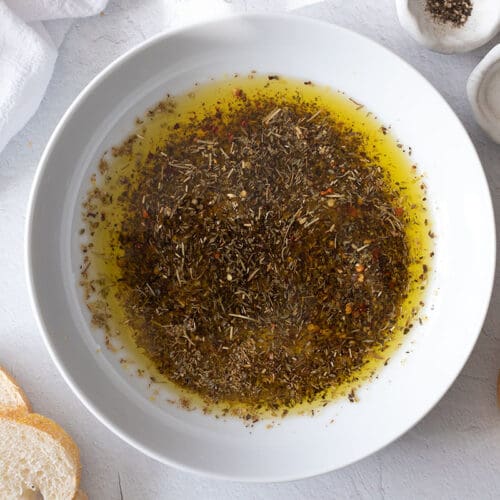 Olive oil bread dip next to slices of bread.