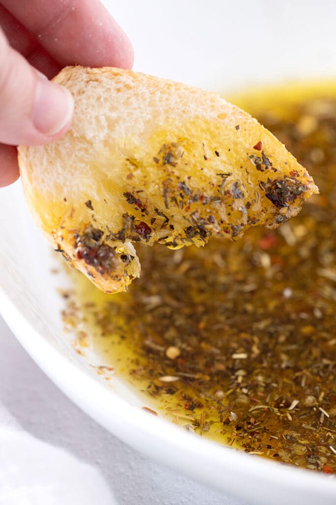 Slice of bread being dipped into olive oil dip.