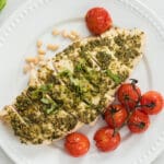 Pesto Chicken on a white plate with tomatoes.