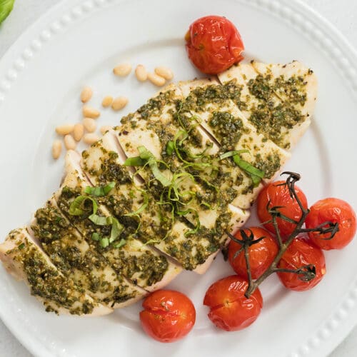 Pesto Chicken on a white plate with tomatoes.