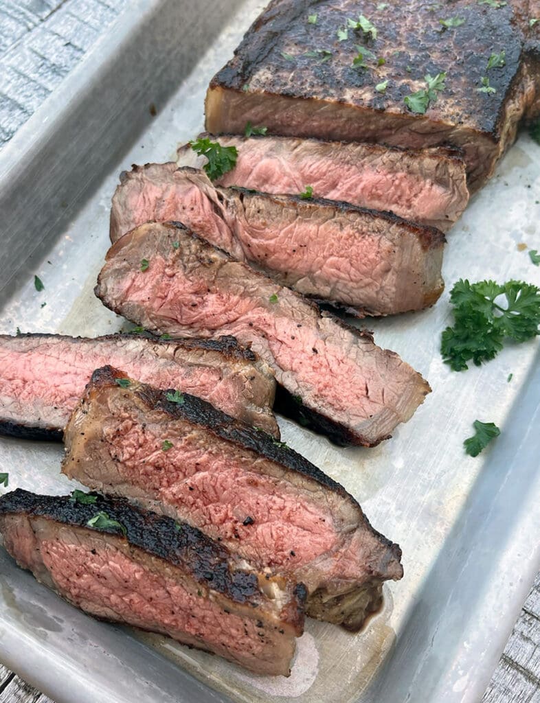 Cut steak on a silver baking sheet.