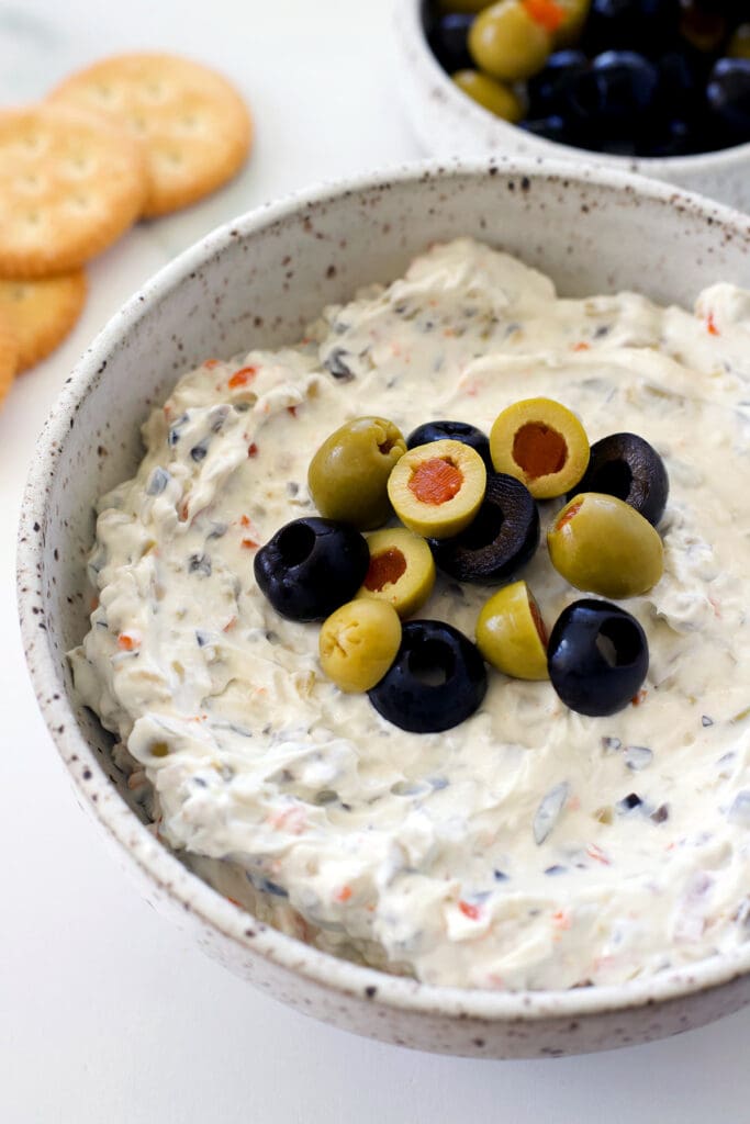olives atop green olive dip in a bowl.