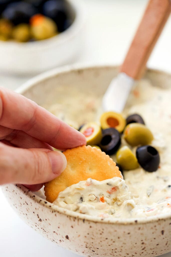 Hand dipping a ritz cracker in dip.