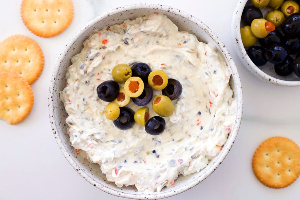 Olive dip in a bowl next to crackers.