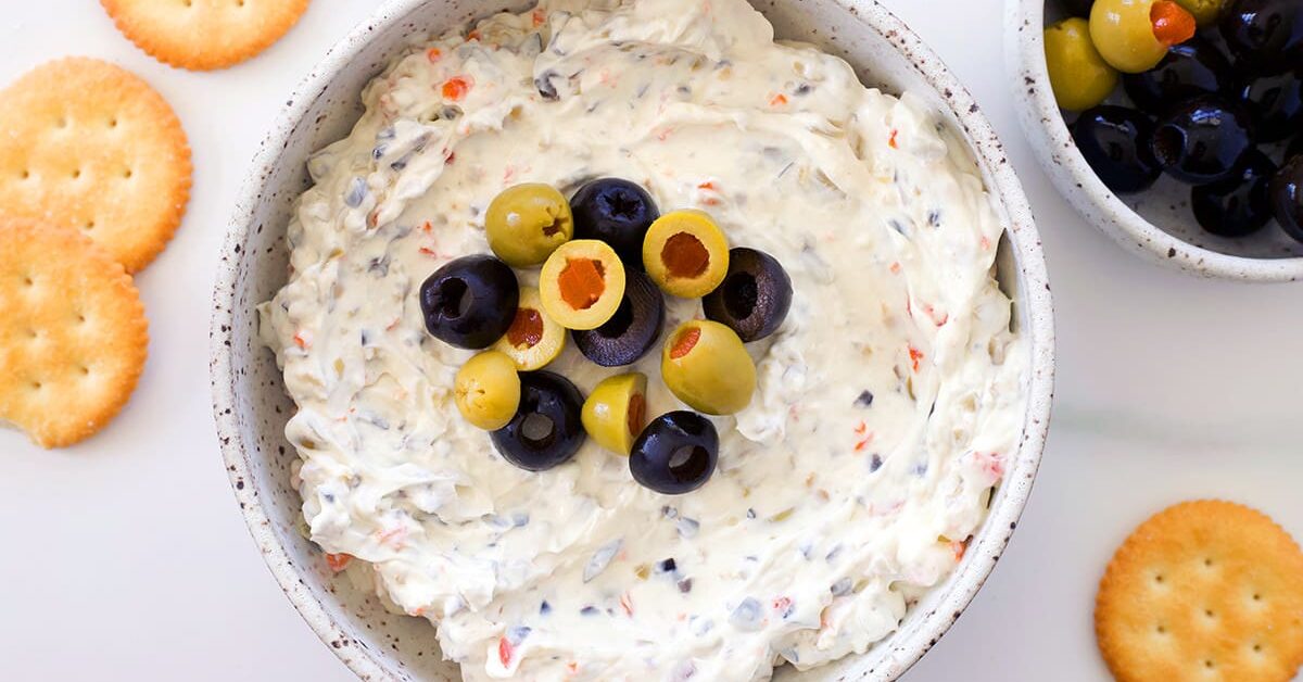 Olive dip in a bowl next to crackers.