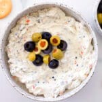 Olive dip in a bowl next to crackers.