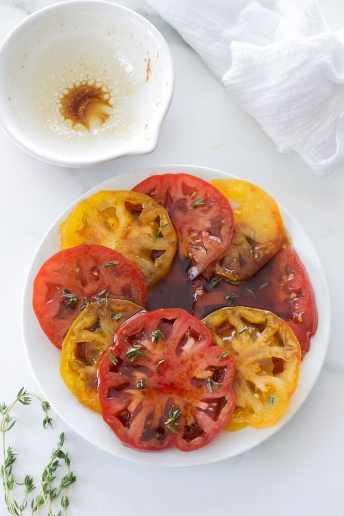 Plate full of marinated heirloom tomatoes cut in half.