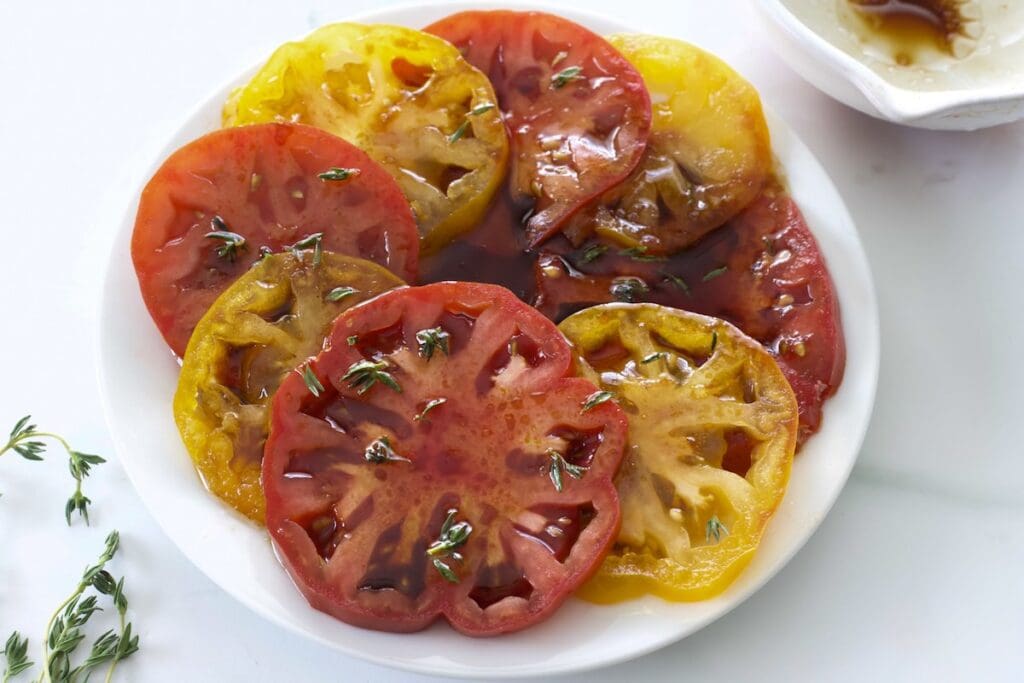 Plate full of marinated heirloom tomatoes cut in half.