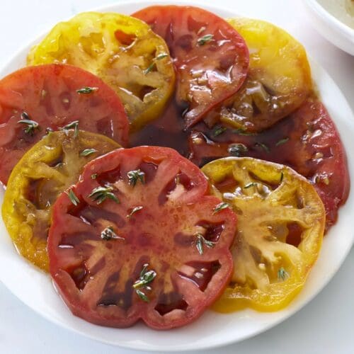 Plate full of marinated heirloom tomatoes cut in half.